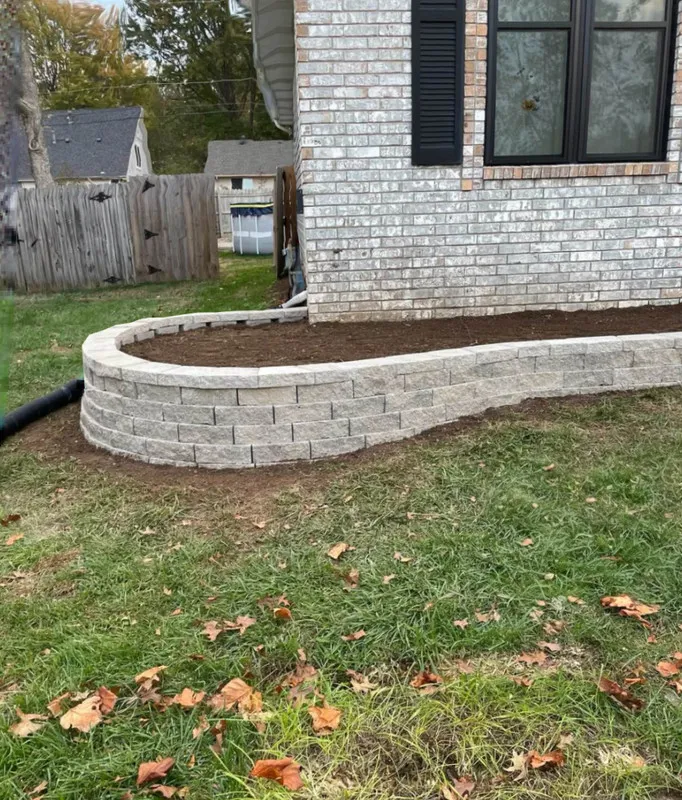 A natural stone retaining wall stabilizing a sloped backyard